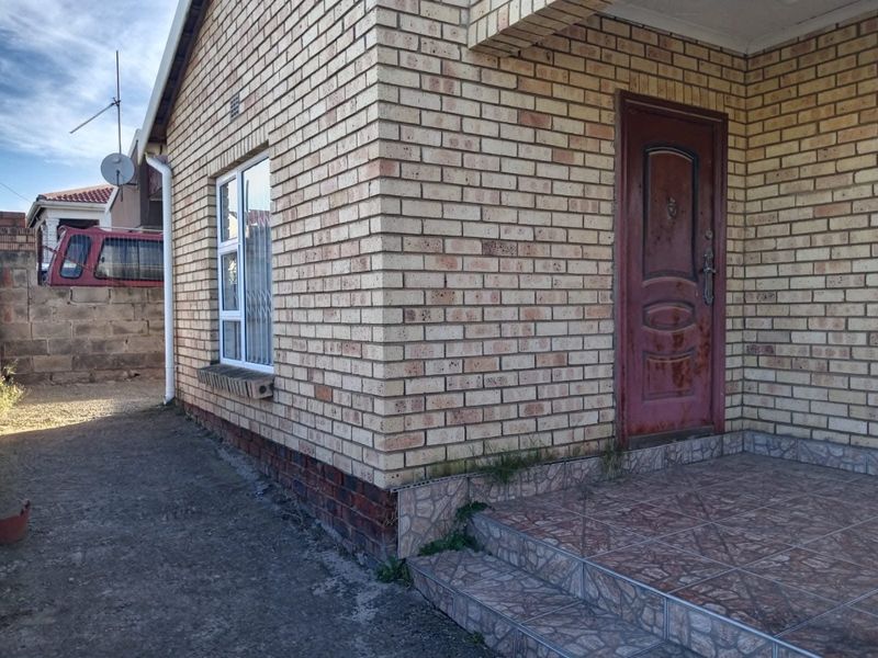 Front entrance of a face brick house featuring a tiled porch area and security gate access.