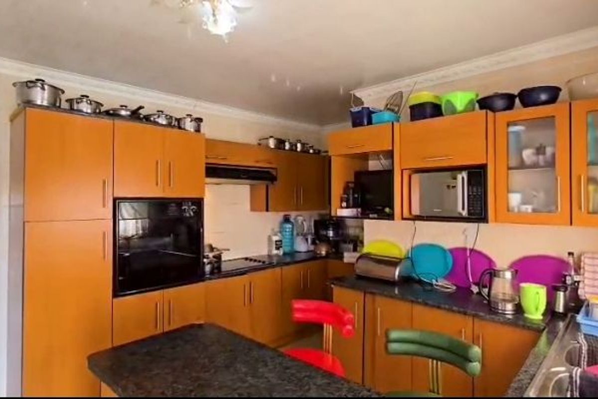 A functional kitchen featuring wood-tone cabinetry, laminate countertops, built-in oven, and an integrated extractor fan with ample storage space.