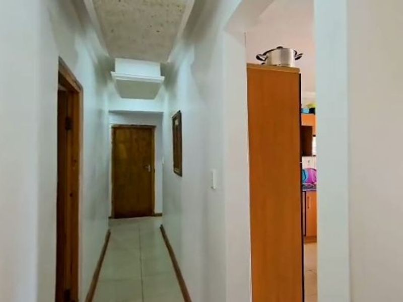 A functional hallway with tiled flooring and wooden door frames, providing access to adjacent rooms within the home.