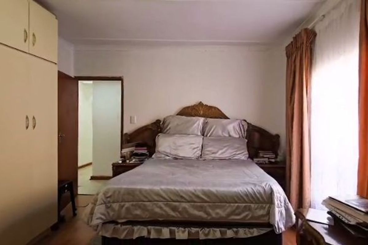 A functional bedroom featuring built-in cupboards and natural light from the window, offering a comfortable space with potential for modern updates.