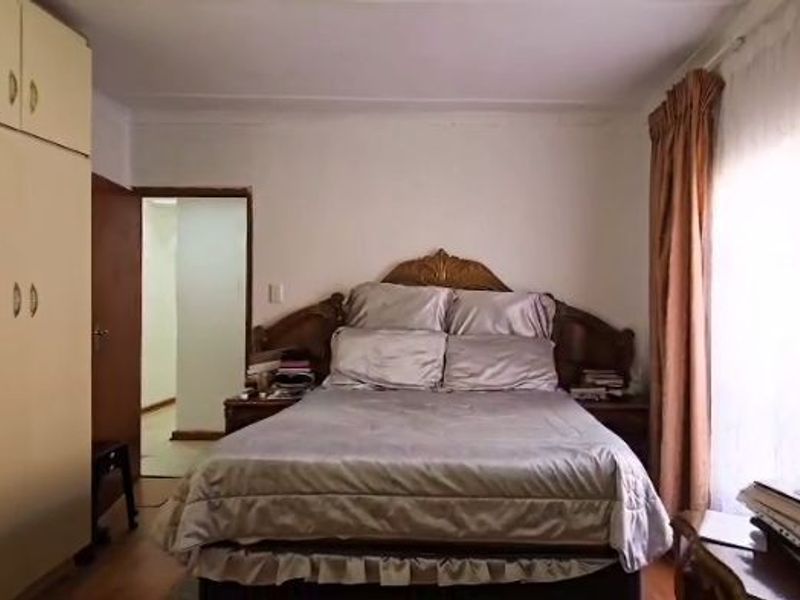 A functional bedroom featuring built-in cupboards and natural light from the window, offering a comfortable space with potential for modern updates.