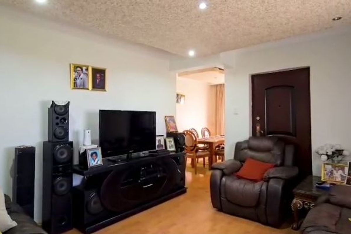 A living room featuring laminate flooring, recessed ceiling lighting, and a textured ceiling finish, with an open transition to the adjacent dining area.