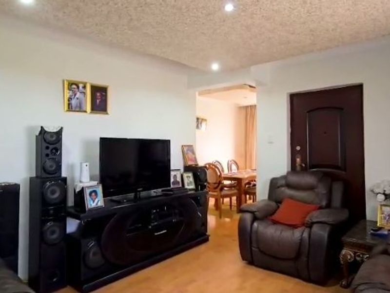 A living room featuring laminate flooring, recessed ceiling lighting, and a textured ceiling finish, with an open transition to the adjacent dining area.