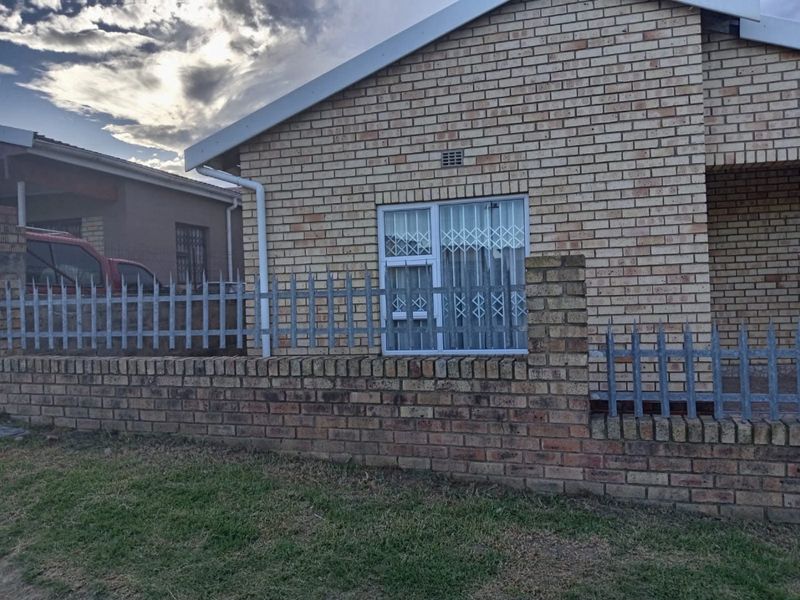 Front elevation of a face-brick house featuring a perimeter brick wall with metal palisade fencing and a secure window entrance.
