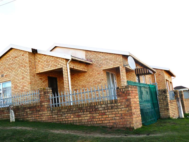 A single-story face brick house featuring a secure perimeter wall, metal fencing, and security bars on the windows.