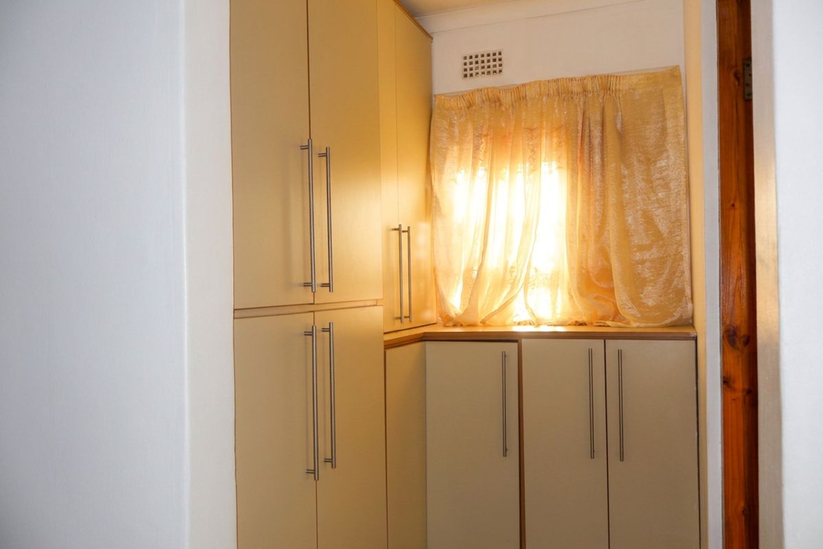 A corner kitchen area featuring built-in cabinetry with modern handles and a small ventilation grille above the window.