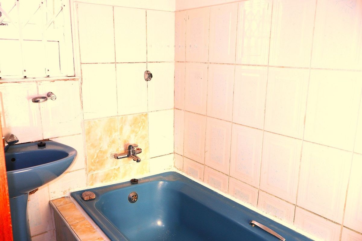 A dated bathroom featuring a blue pedestal basin and matching bathtub with wall-mounted taps and ceramic tiling throughout.