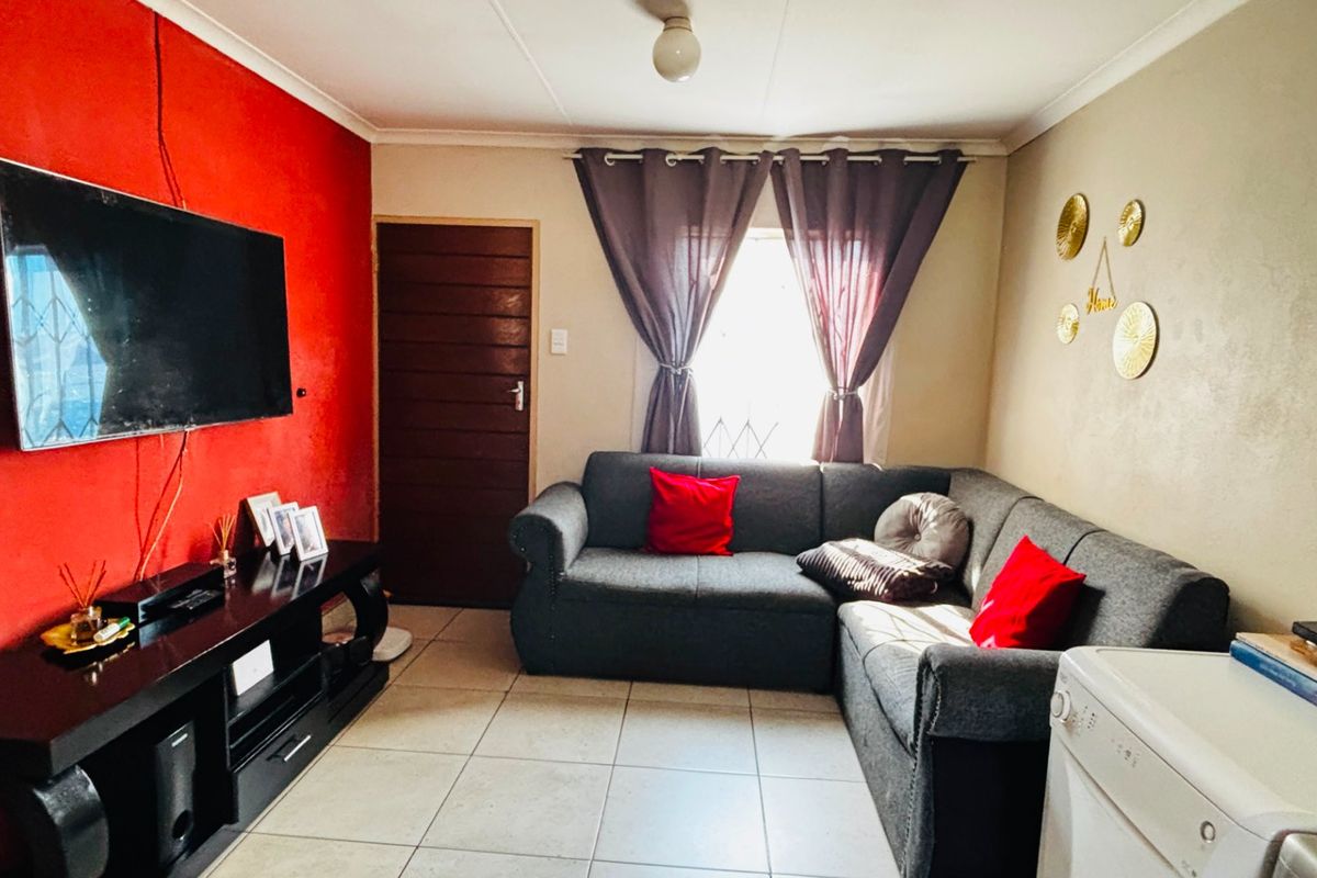 A functional living room featuring tiled flooring and a neutral layout, providing a comfortable space for relaxation and entertainment.