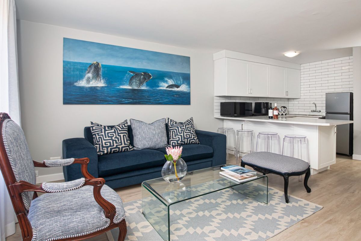 A bright open-plan living area featuring a modern kitchen with white cabinetry, subway tile backsplash, and durable laminate flooring throughout.