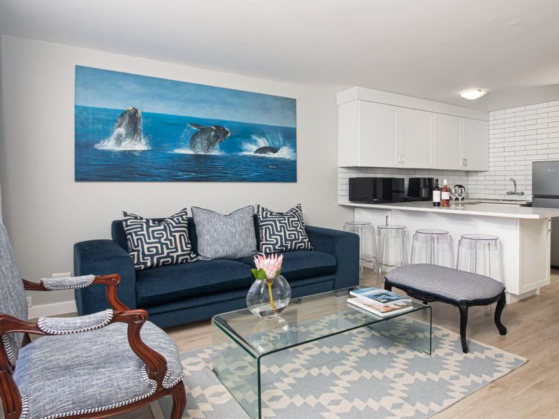 A bright open-plan living area featuring a modern kitchen with white cabinetry, subway tile backsplash, and durable laminate flooring throughout.