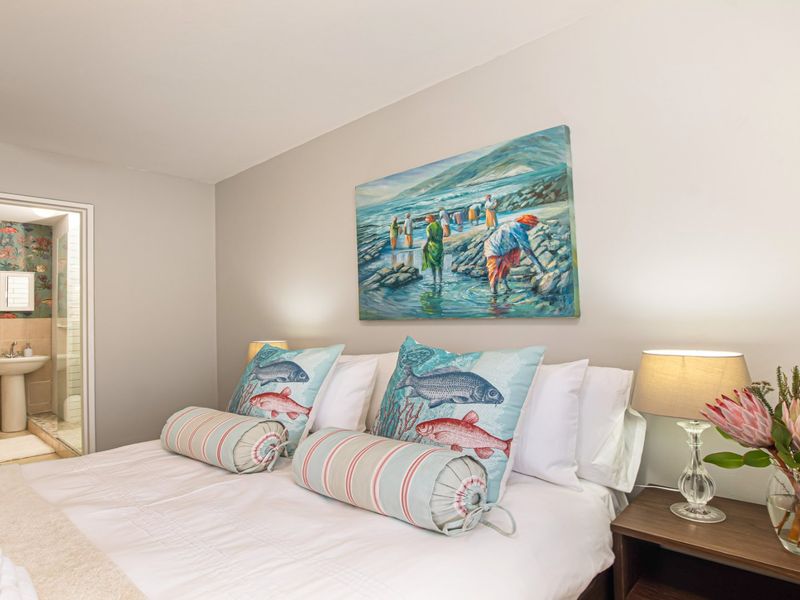 A well-maintained bedroom featuring an adjoining en-suite bathroom with a pedestal basin, toilet, and shower.