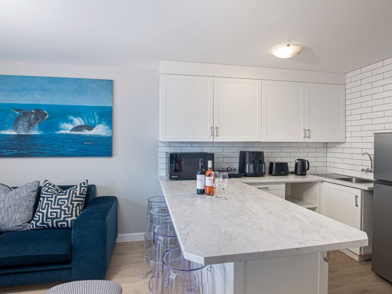 Modern open-plan kitchen featuring white shaker cabinetry, marble-effect countertops, and a classic subway tile backsplash, seamlessly integrated with the living area.