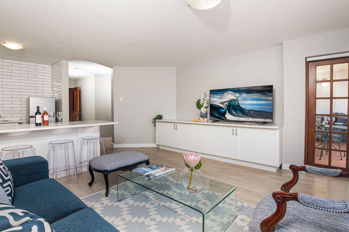 Open plan living area featuring a modern kitchen island with subway tile backsplash, built-in cabinetry, and access to a balcony through a classic french door.