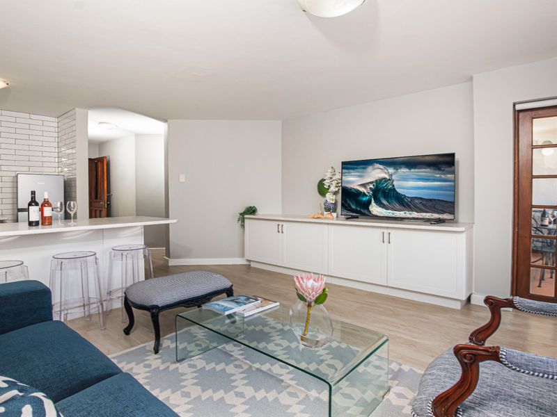Open plan living area featuring a modern kitchen island with subway tile backsplash, built-in cabinetry, and access to a balcony through a classic french door.