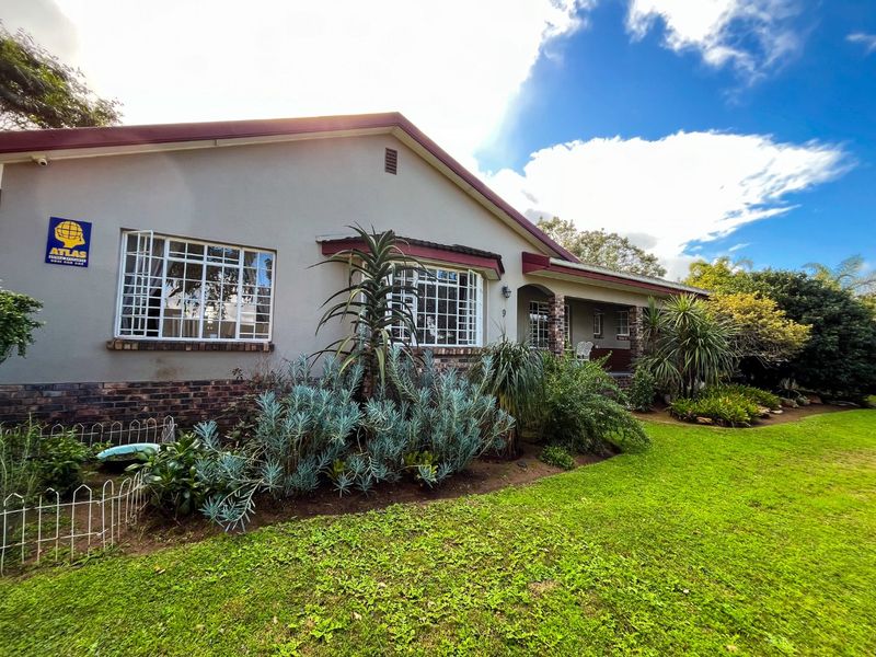 A well-maintained single-story house featuring a brick and plaster facade, security-barred windows, and a spacious front garden with established landscaping.