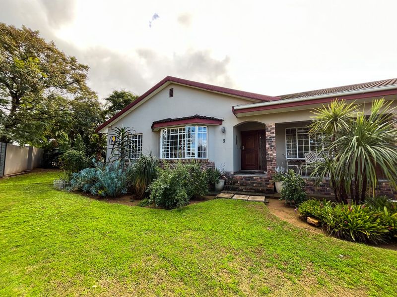 A well-maintained single-story house featuring a brick facade, a prominent bay window, and a covered entrance set within a landscaped front garden.
