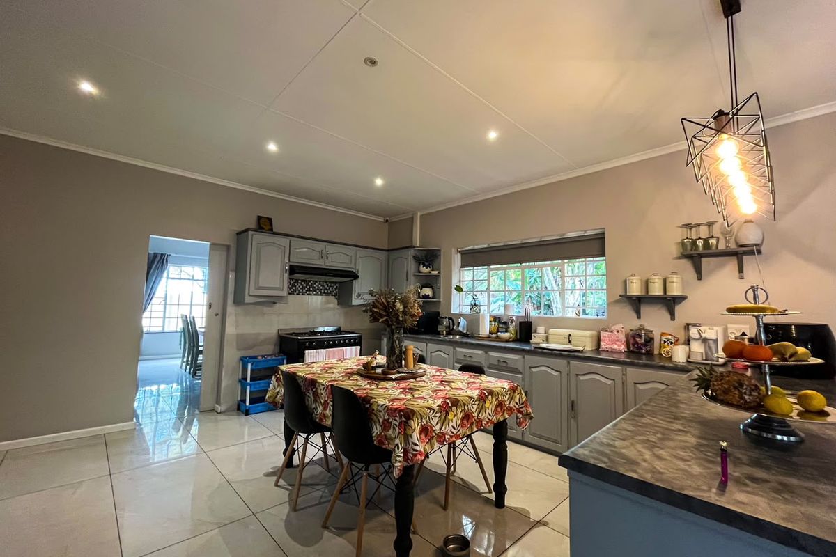 A well-lit kitchen featuring grey cabinetry, tiled flooring, and a gas stove, with an open-plan layout connecting to the adjacent dining area.