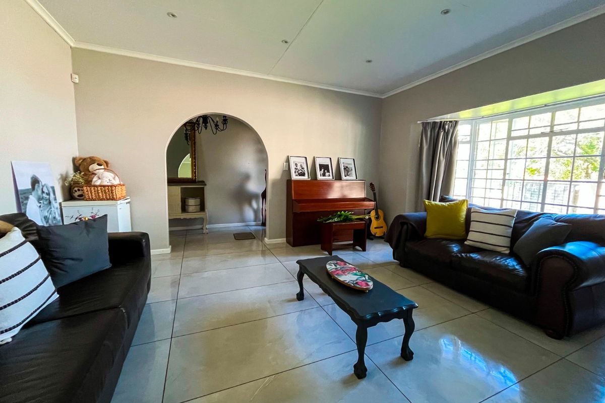 Spacious living room featuring large format floor tiles, a distinctive arched entryway, and a bright bay window allowing for ample natural light.