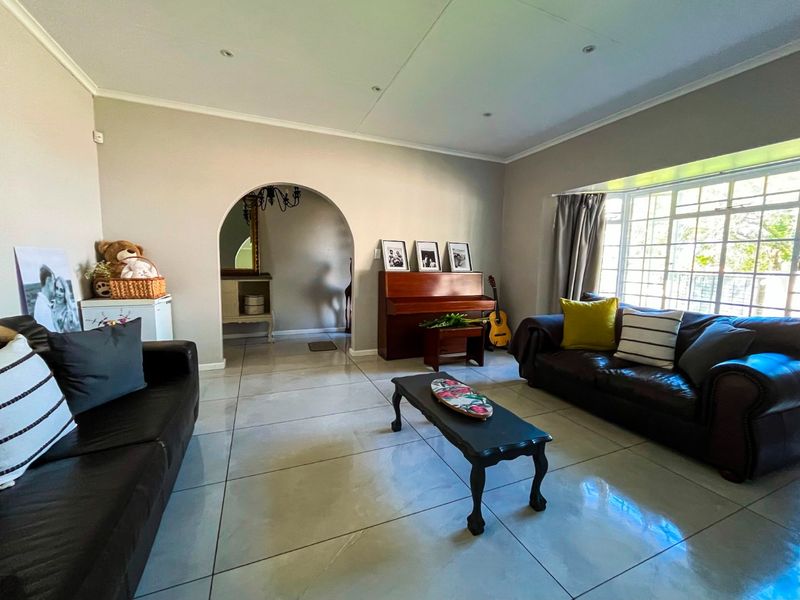 Spacious living room featuring large format floor tiles, a distinctive arched entryway, and a bright bay window allowing for ample natural light.