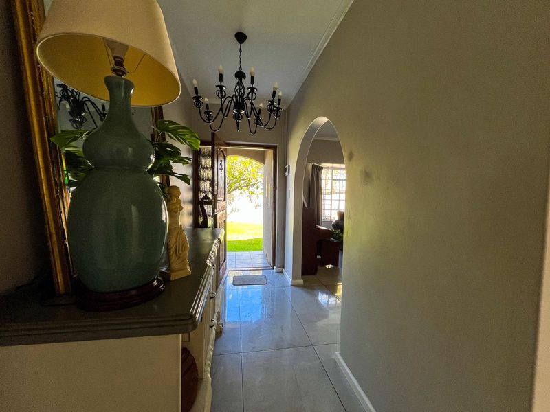 Entrance hallway featuring tiled flooring, an arched transition to the living area, and a decorative wrought iron chandelier.