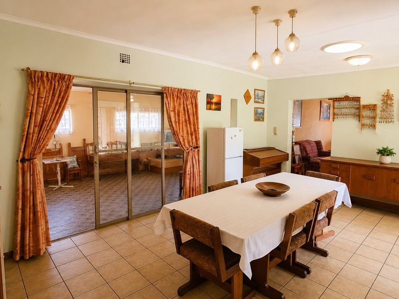 Spacious dining area featuring tiled flooring, pendant lighting, and a sliding glass door providing access to an adjacent room.
