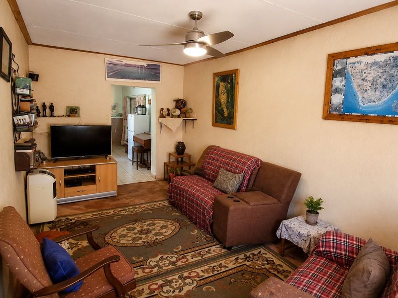 A cozy living room featuring a ceiling fan and direct access to the adjacent kitchen area.