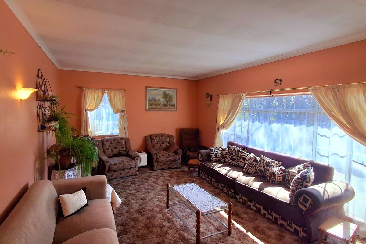 A spacious living room featuring large windows that provide ample natural light, finished with coved ceilings and warm-toned wall paint.