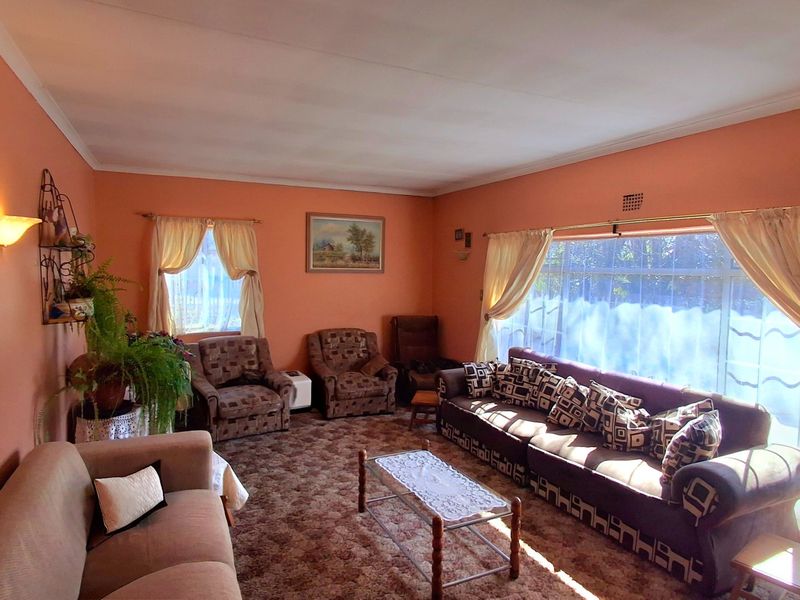 A spacious living room featuring large windows that provide ample natural light, finished with coved ceilings and warm-toned wall paint.