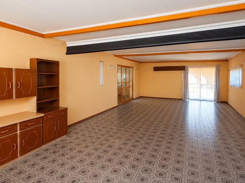 Spacious, empty living area featuring tiled flooring, built-in cabinetry, and a sliding glass door providing natural light.