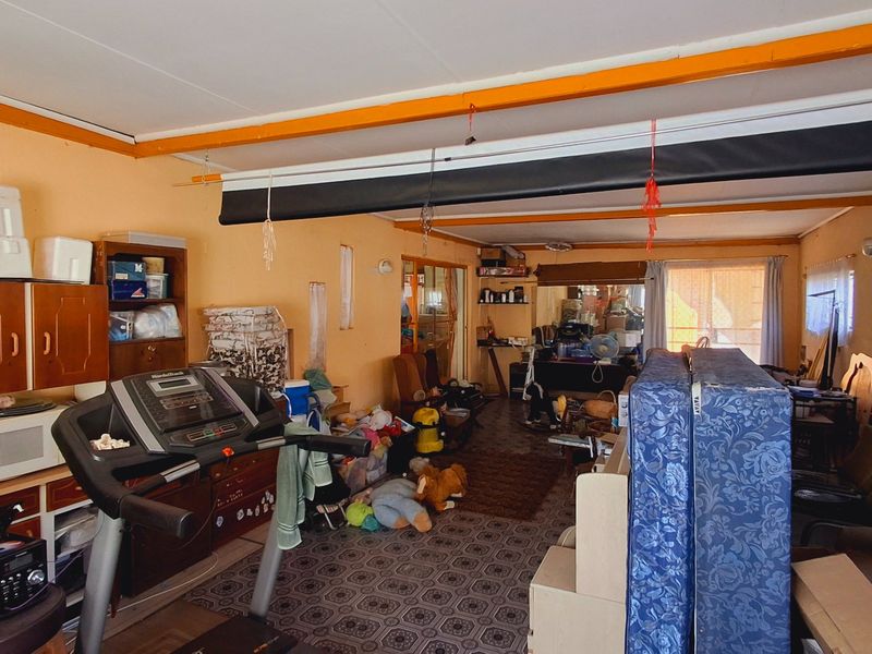A multi-purpose living area featuring built-in cabinetry, a projector screen, and patterned vinyl flooring, offering potential for renovation and modernization.