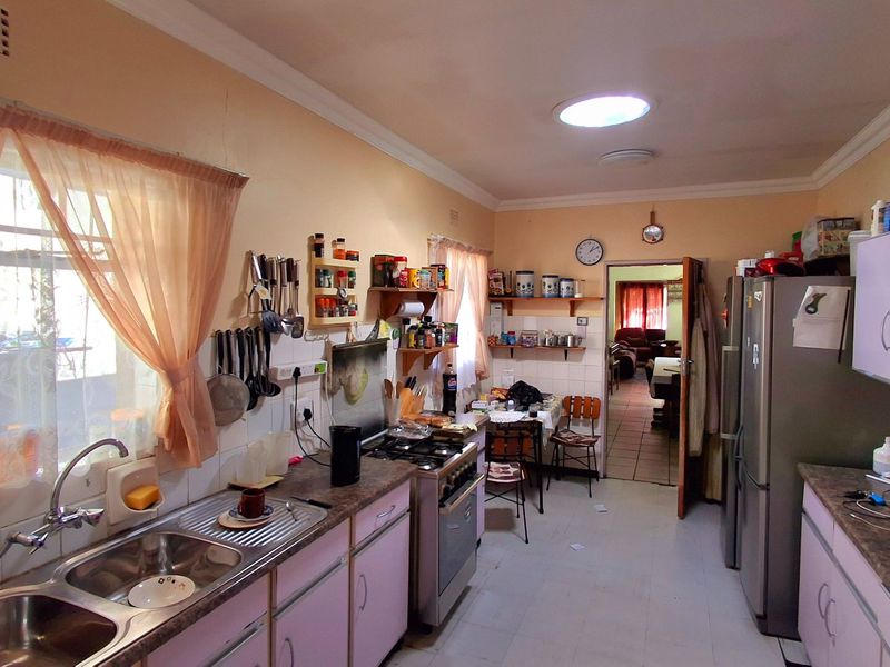 A functional kitchen featuring laminate countertops, double bowl sink, and freestanding stove, with potential for modernization to enhance the space.