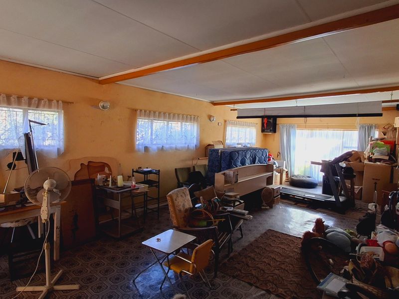 Spacious living area featuring vinyl flooring, exposed ceiling beams, and large sliding glass doors providing natural light and access to the exterior.