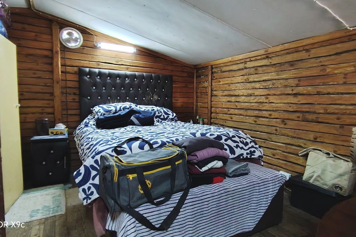 A rustic bedroom featuring timber log walls and a sloped ceiling, offering a cozy cabin-style atmosphere.