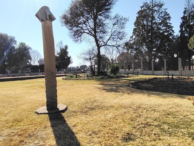 A spacious garden area featuring mature trees, landscaped garden beds, and secure perimeter fencing.