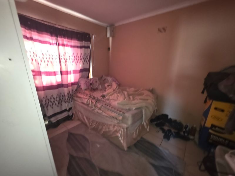 A compact bedroom featuring tiled flooring and cove cornicing, currently requiring cosmetic updates to the wall finishes.
