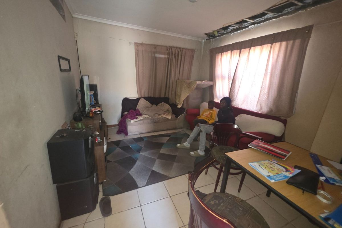 A living room area featuring tiled flooring and a damaged ceiling requiring repair and cosmetic attention to restore the space.