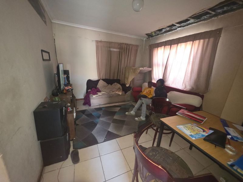 A living room area featuring tiled flooring and a damaged ceiling requiring repair and cosmetic attention to restore the space.