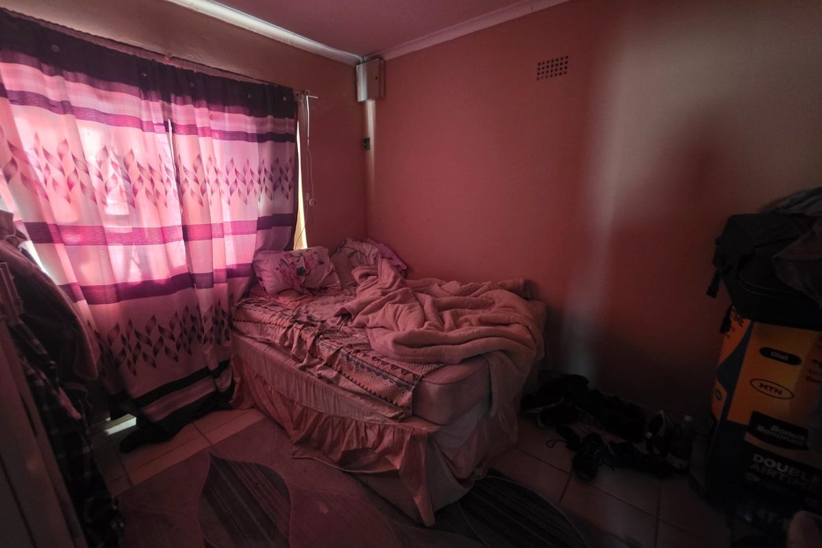 A bedroom featuring tiled flooring and standard wall finishes, currently requiring maintenance and improved lighting to enhance the space.