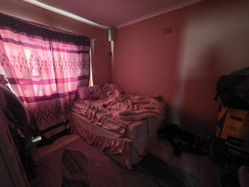 A bedroom featuring tiled flooring and standard wall finishes, currently requiring maintenance and improved lighting to enhance the space.