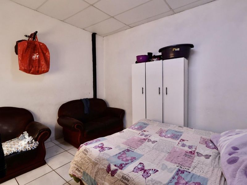 A bedroom featuring tiled flooring and a drop ceiling, currently utilized as a living and sleeping space.