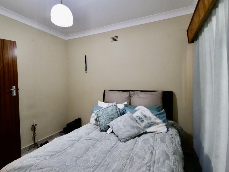 A standard bedroom featuring neutral wall finishes, a timber door, and a timber curtain pelmet with integrated ventilation.