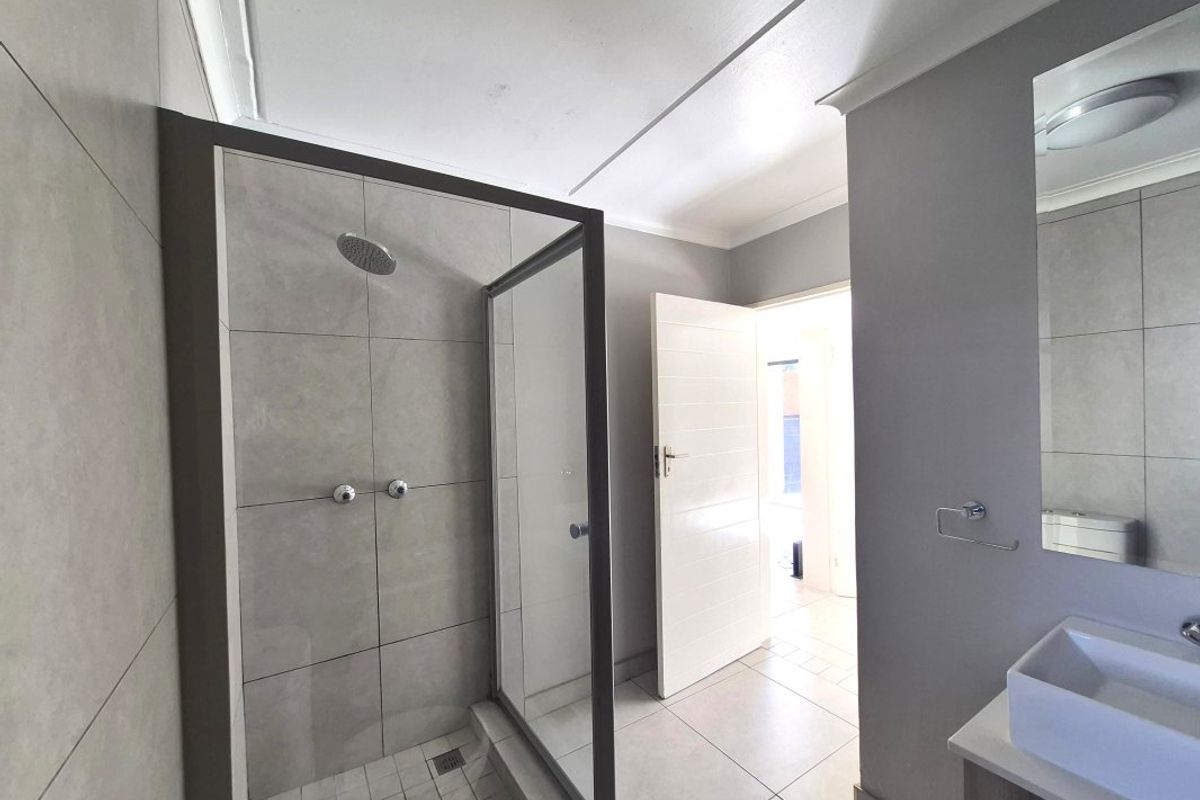 Modern bathroom featuring a walk-in shower with glass enclosure, tiled finishes, and a wall-mounted vanity basin.