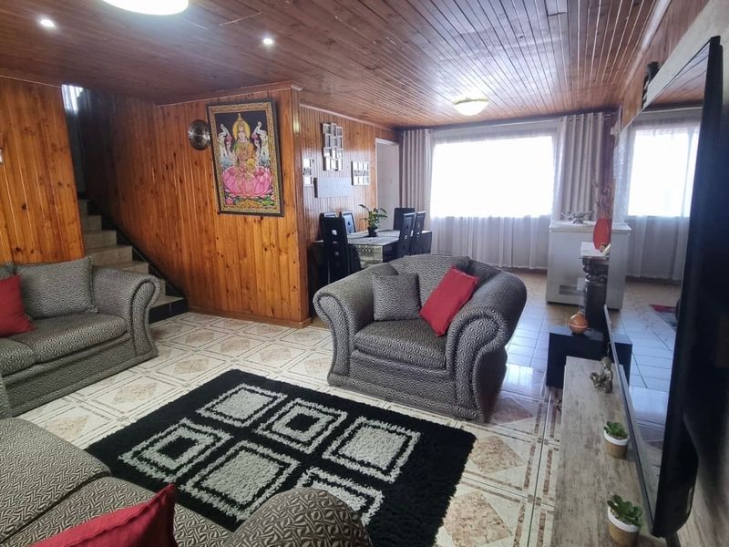 Open plan living and dining area featuring timber wall paneling, a timber ceiling, and tiled flooring with an integrated staircase.
