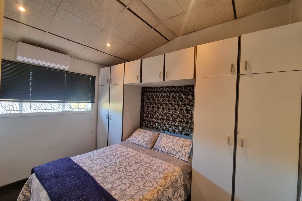 A bedroom featuring extensive built-in cabinetry, a split-system air conditioner, and a drop ceiling with recessed lighting.