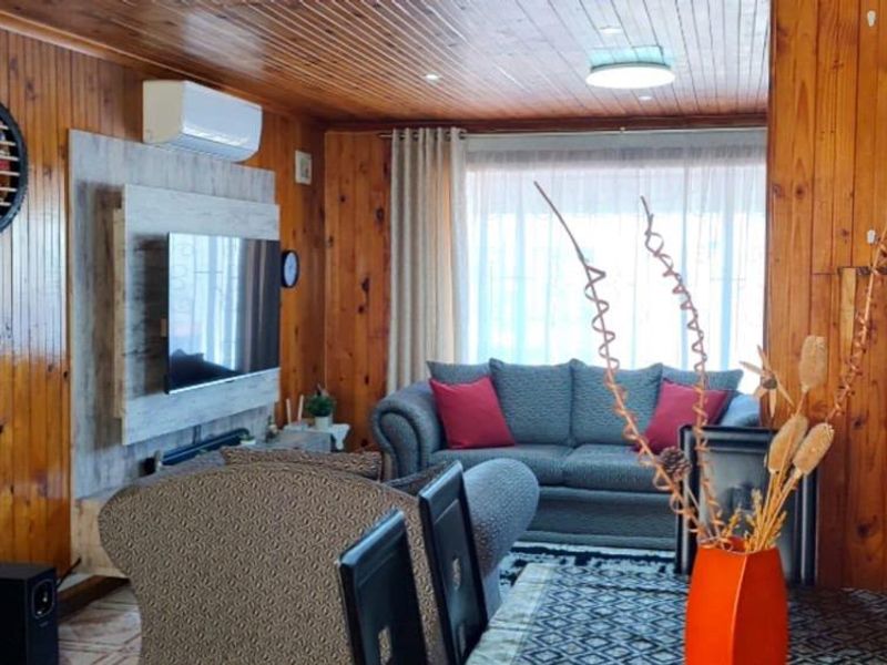 A cozy living room featuring extensive timber wall and ceiling paneling, equipped with a split-system air conditioner and recessed lighting.