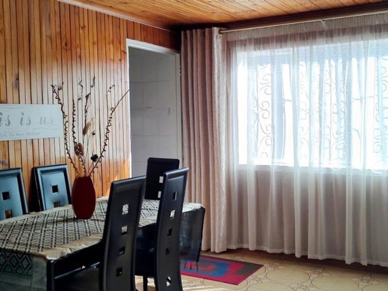 Dining area featuring warm timber wall paneling and a matching timber ceiling, complemented by tiled flooring and natural light from the window.