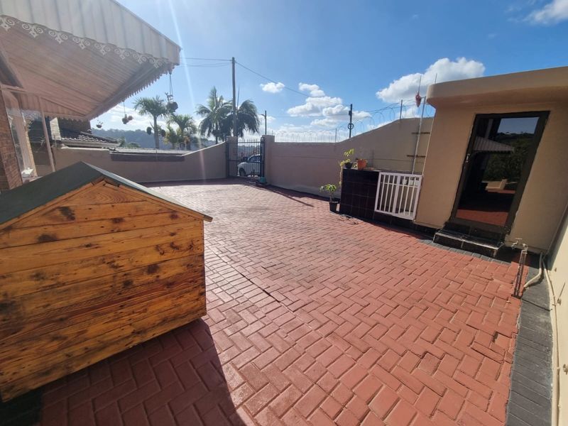 A spacious paved outdoor patio area featuring perimeter walls with security fencing and direct access to the main dwelling.