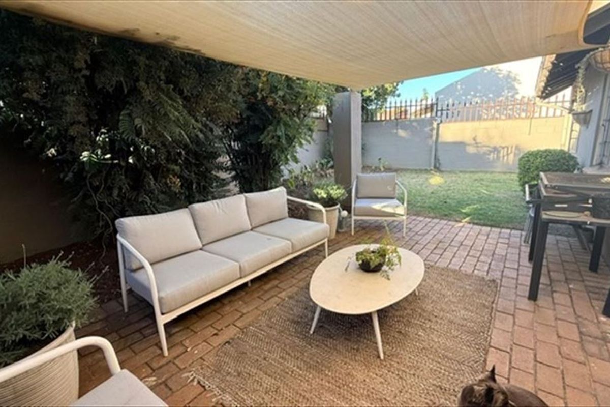 A covered outdoor patio area featuring brick paving and a shade sail, providing a functional space for outdoor relaxation and entertaining.