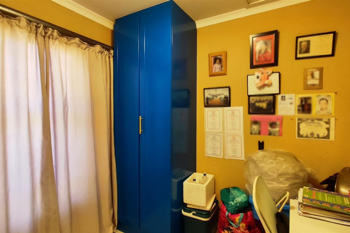 A bedroom featuring a tall, high-gloss blue built-in wardrobe and neutral wall finishes, offering functional storage space.