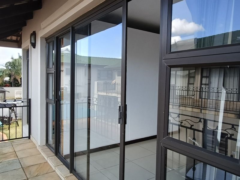 A covered balcony featuring tiled flooring, wrought iron railings, and large sliding glass doors providing access to the interior living space.